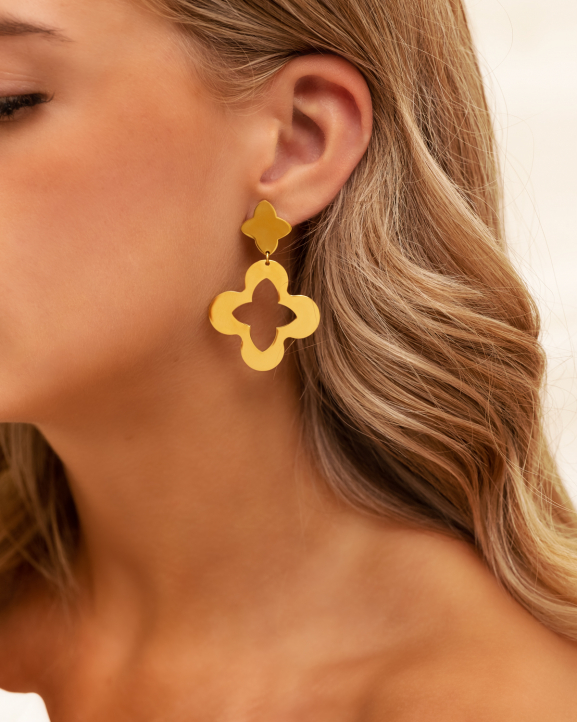Model draagt gouden clover oorbellen