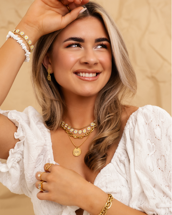 Model draagt gouden sieraden met bloemetjes