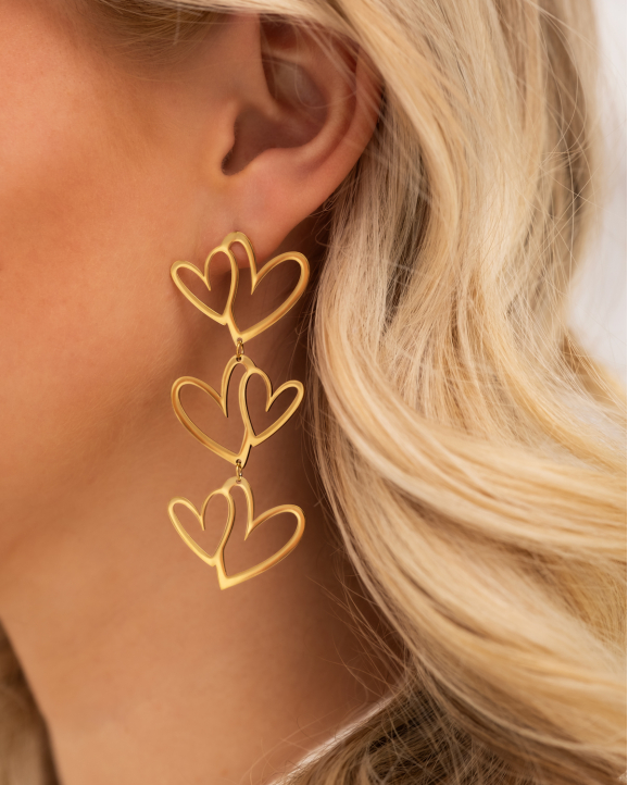 Model draagt gouden hartjes oorbellen