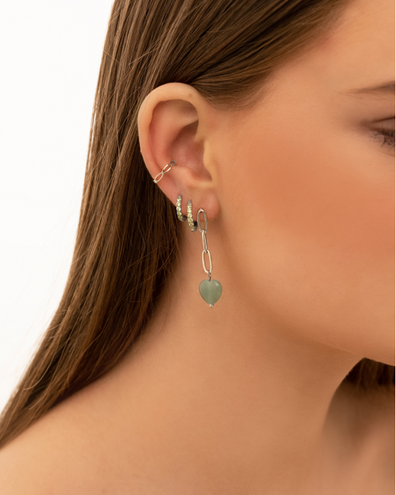 Model draagt oorbellen mix van groene en zilveren oorbellen