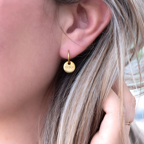Gouden oorbelletjes met vier initialen in het oor