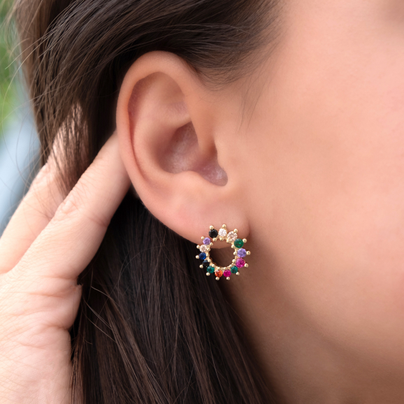 Vrouw draagt ronde regenboog stud oorbellen in het oor