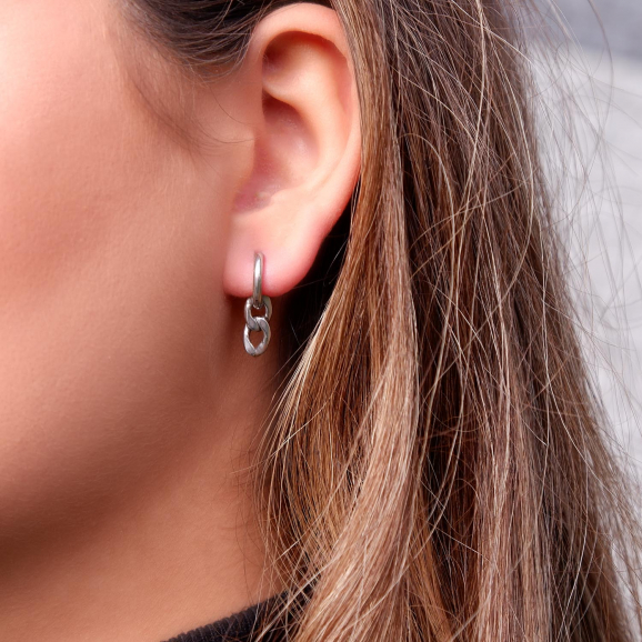 Vrouw draagt mooie schakel oorbellen in het oor voor een complete look