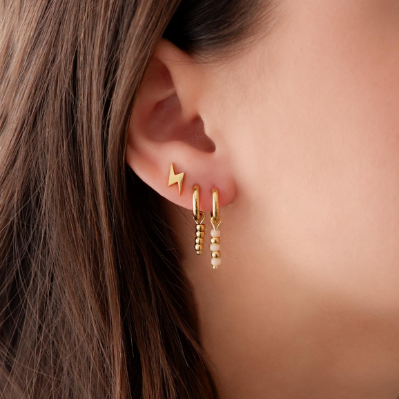 Trendy gouden oorbellen in het oor met gouden details