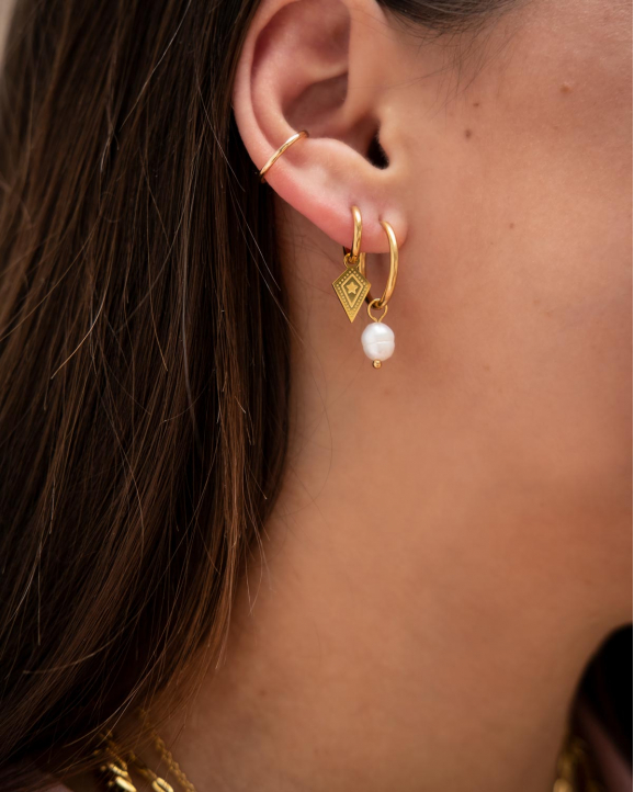 Mooie parel oorbellen in het oor van het model gecombineerd met oorbellen met hangertje