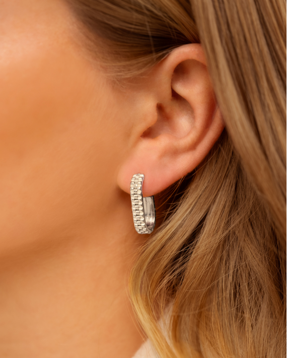 Model draagt zilveren oorbellen met print in oor