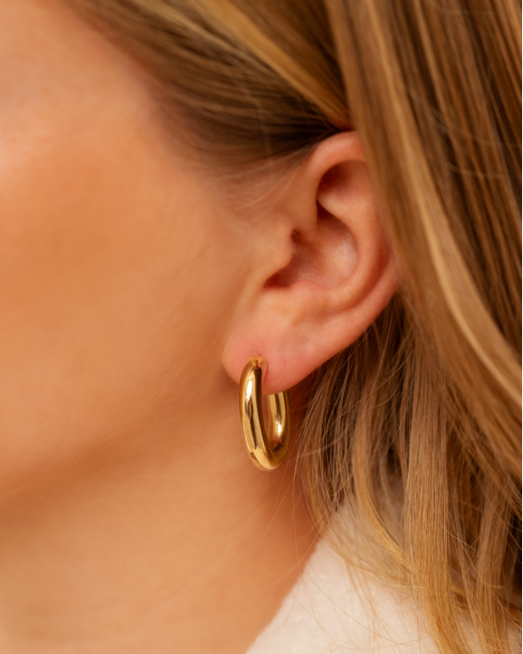 Model draagt gouden hoops in oor