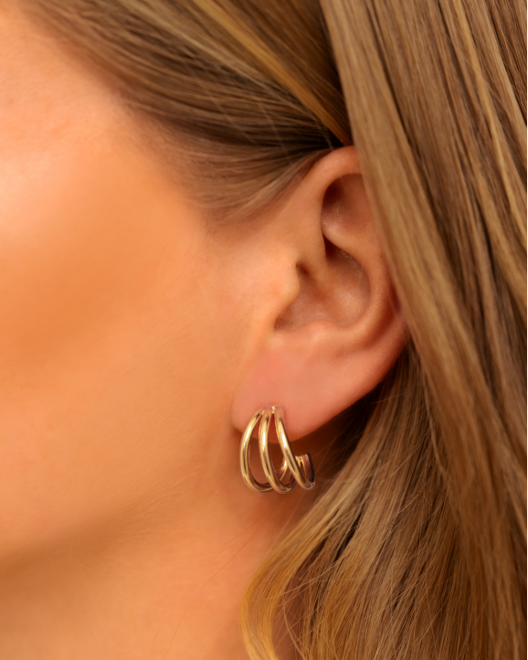 Model draagt gouden oorringen in oor