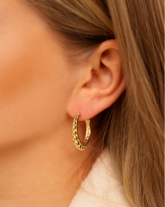 Gouden oorringen bij model in oor