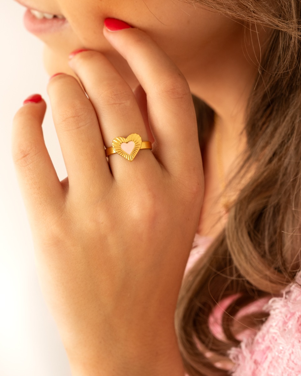 Model draagt gouden ring met roze hartje