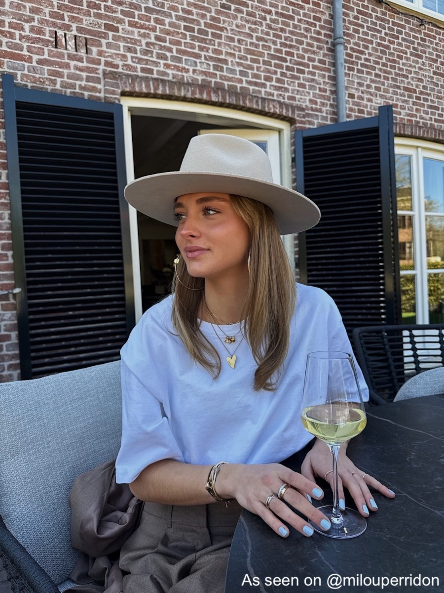 Influencer met gouden kettingen, hoops en hoed
