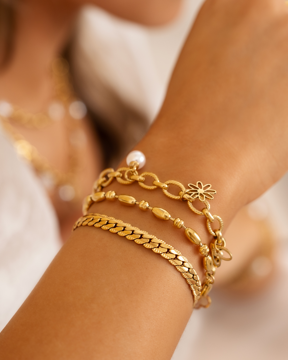 Model draagt gouden armparty met drie armbanden