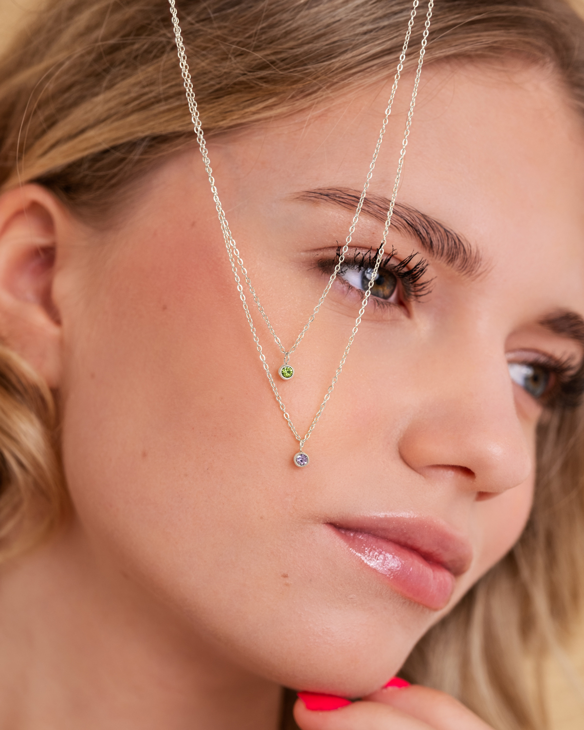 Zilveren birthstone ketting op gezicht