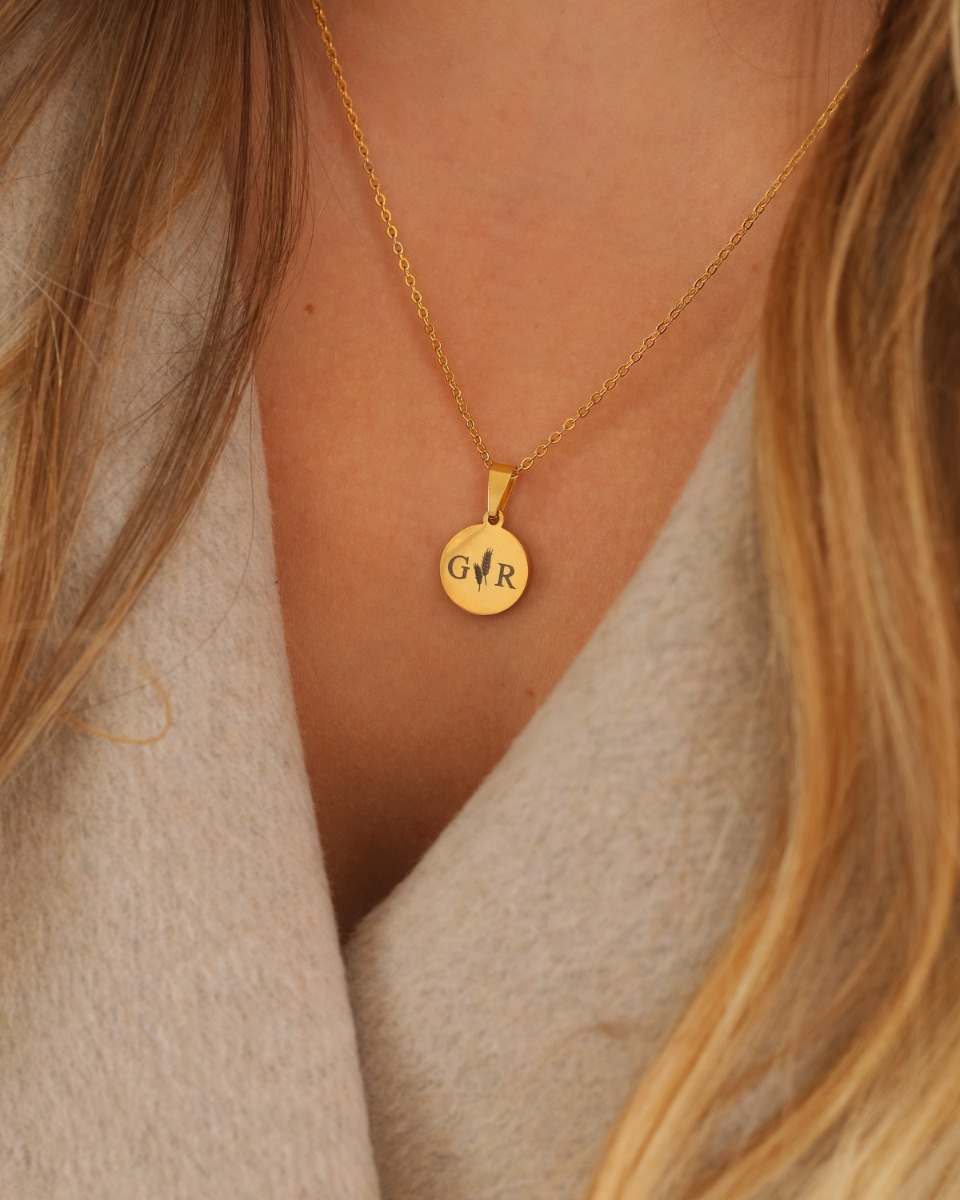 gouden ketting met twee letters en graantjes er tussen
