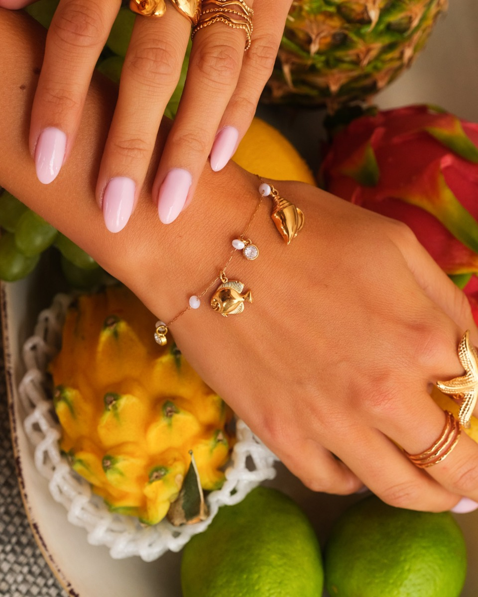 Gouden bedelarmband met witte steentjes en zee bedels