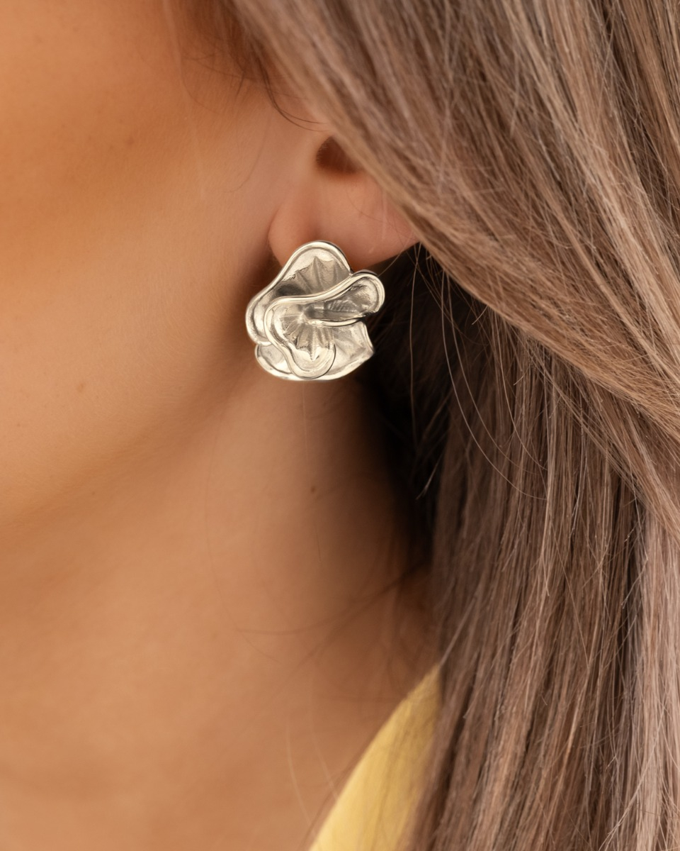 Model draagt zilveren bloemen studs
