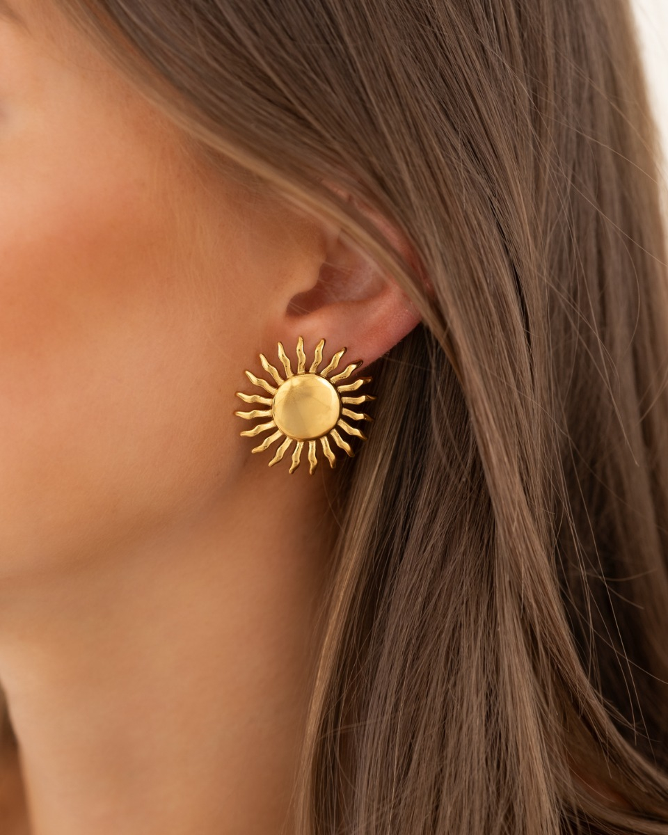 Model draagt gouden studs met zon