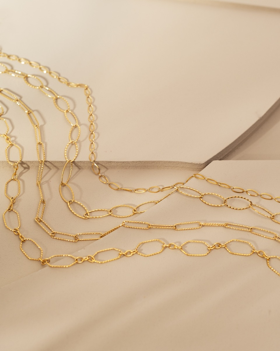 gouden lange chain kettingen op beige stenen