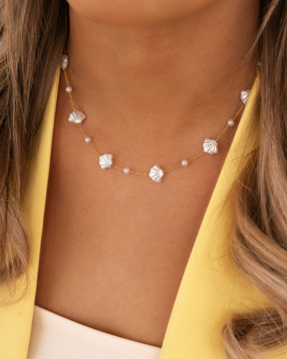 Model draagt gouden schelpen ketting met parels