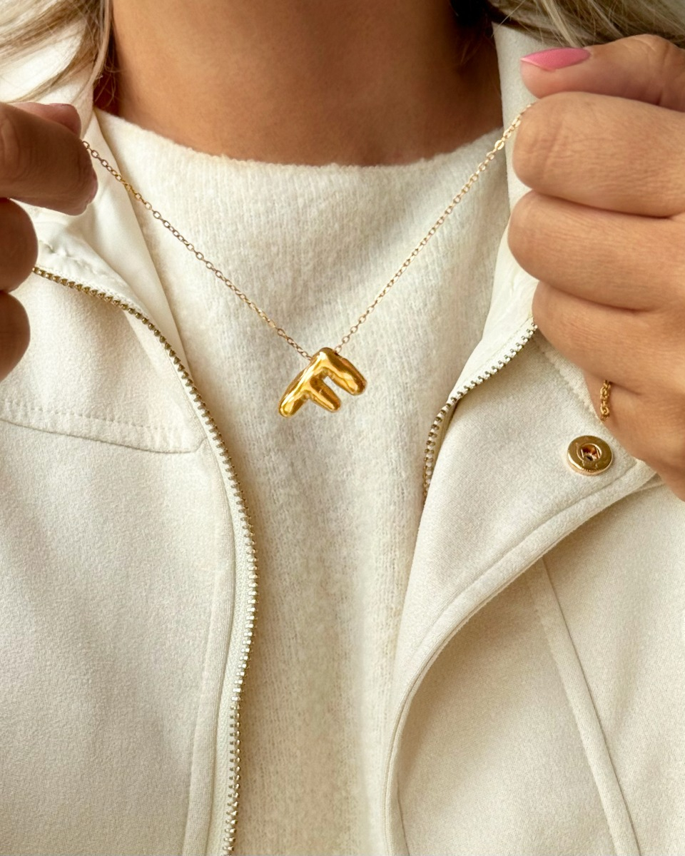 Model draagt gouden letter ketting