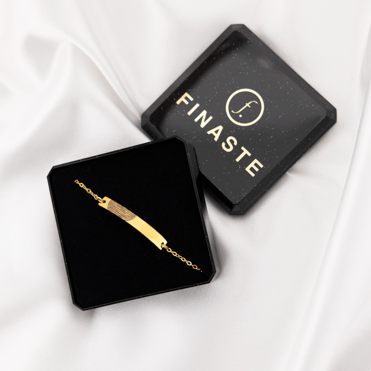 graveerbare gouden bar armband met vingerafdruk in doosje op satijnen achtergrond