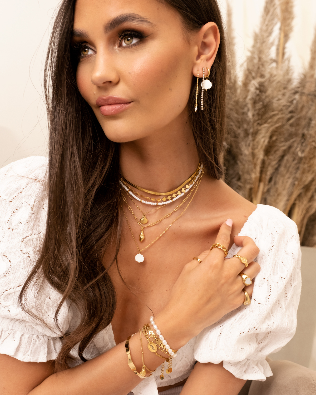 Model draagt gouden sieraden en parelarmband