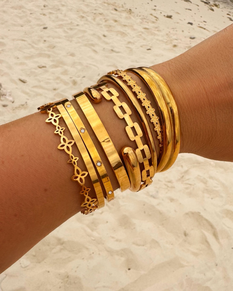 gouden armparty van bangles op het strand