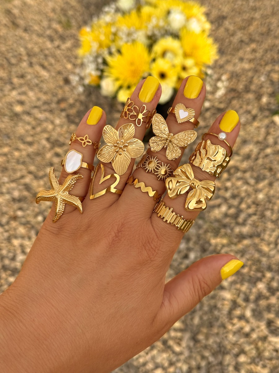 gouden ringen combinatie met gele bloemen op de achtegrond