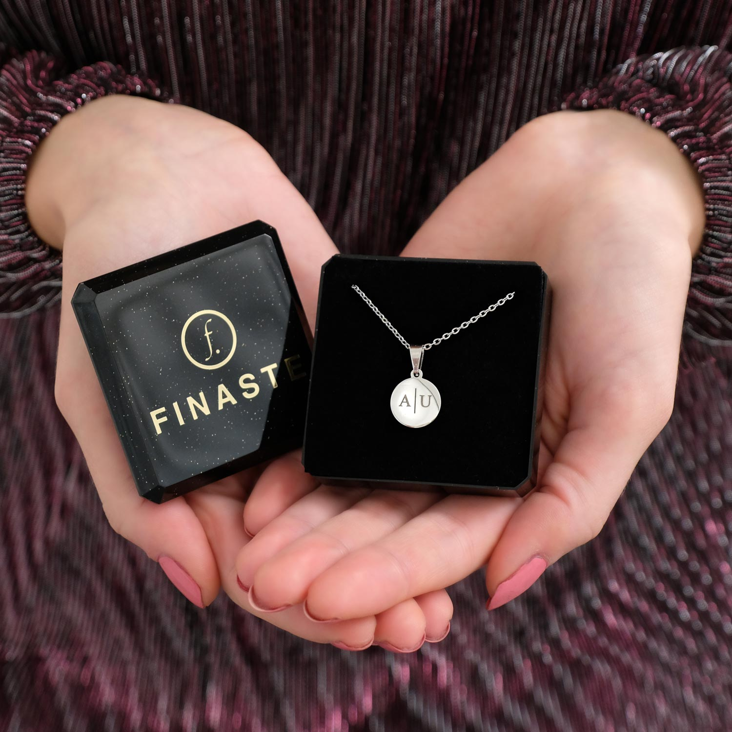 zilveren ketting  met initialen op coin in doosje in handen