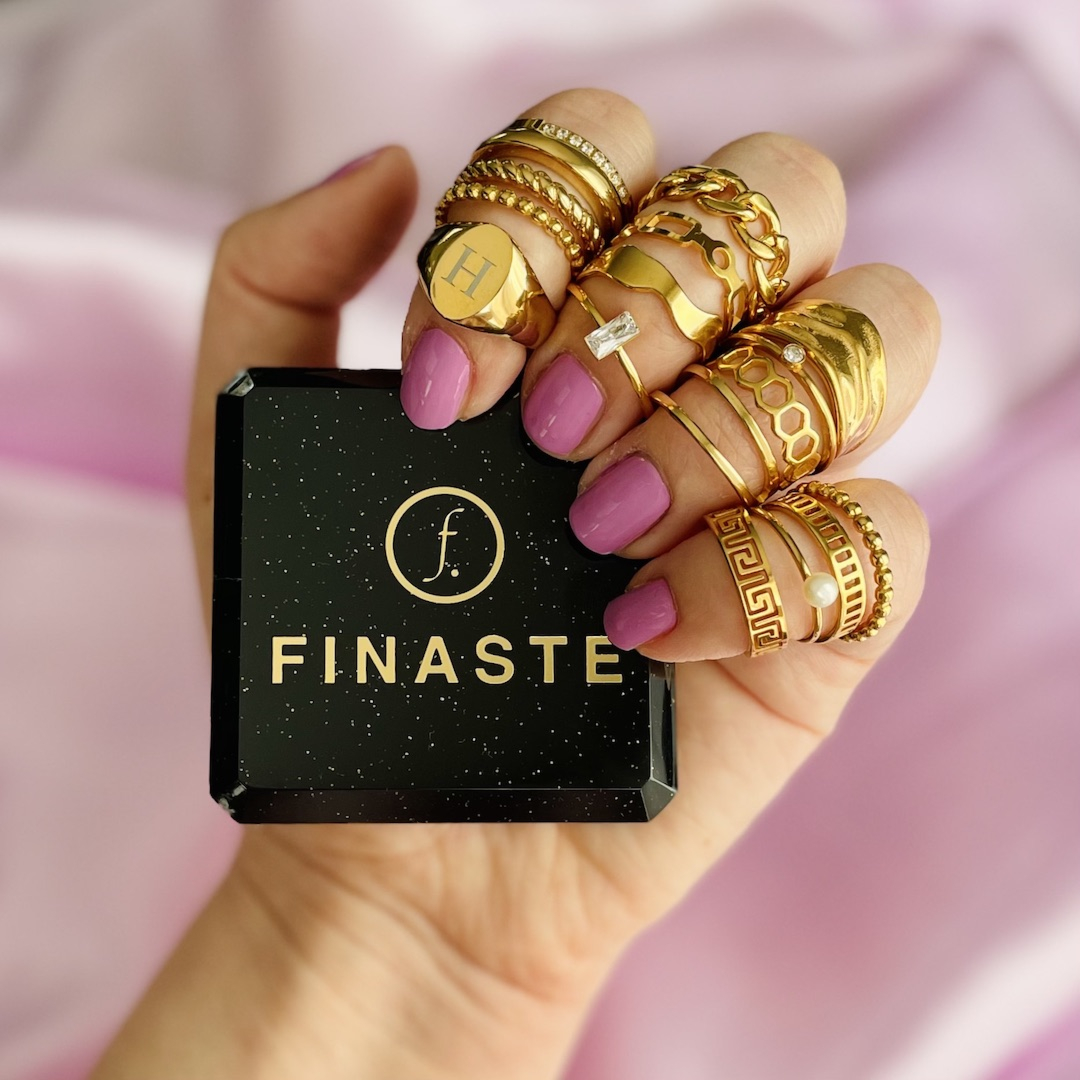 Mooie trendy gouden ringen om de hand van het model met in haar hand het Finaste sieradendoosje
