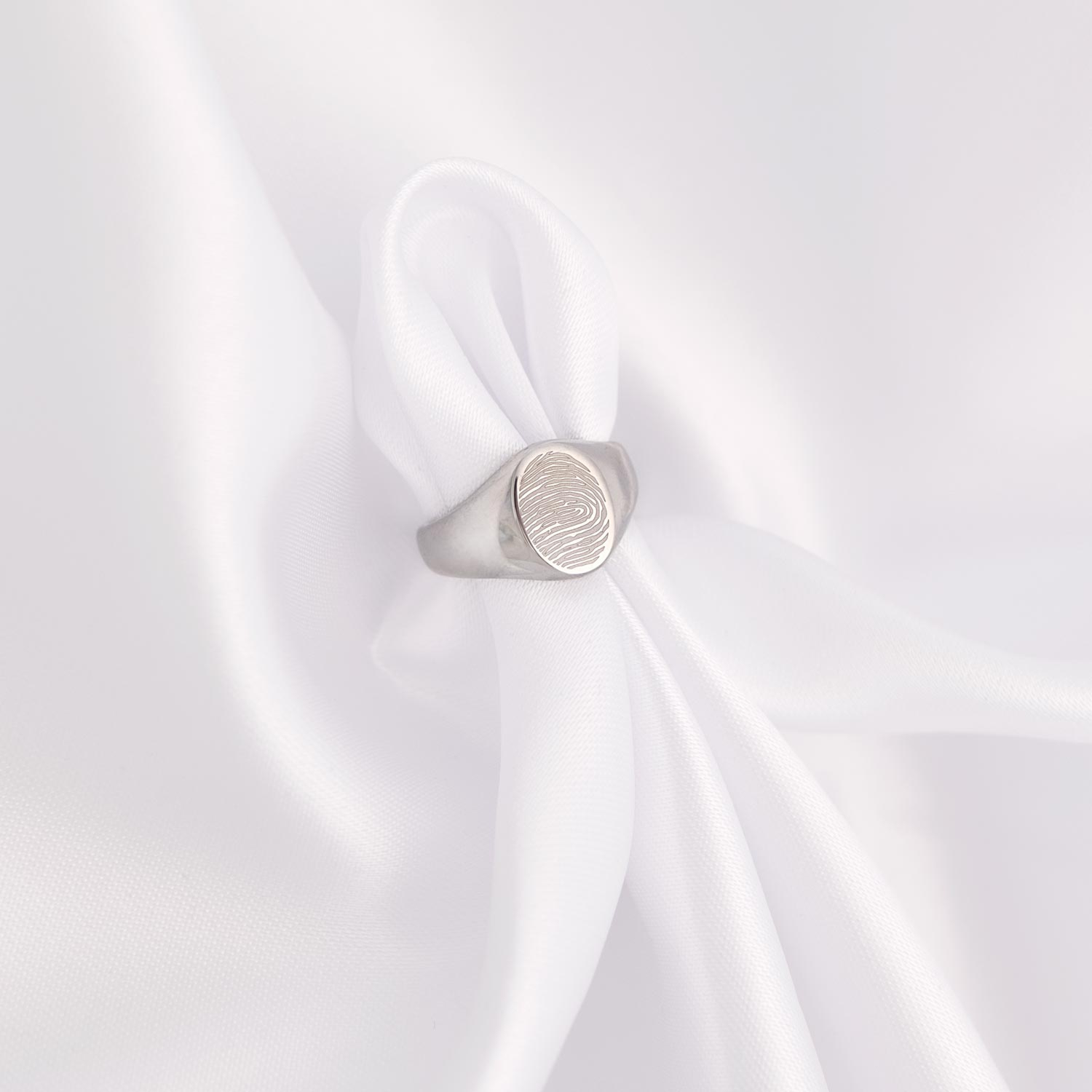 Zegelring met vingerafdruk op wit satijn