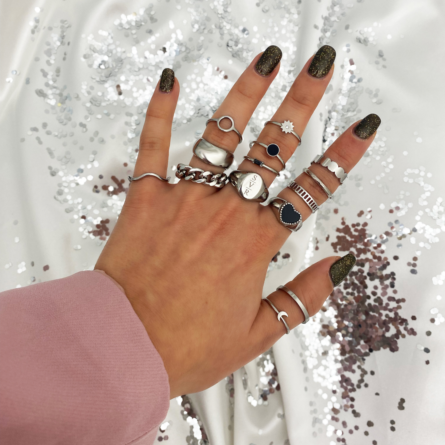 zilveren ring party met zwarte details en open ring om vingers vrouw met glitter achtergrond