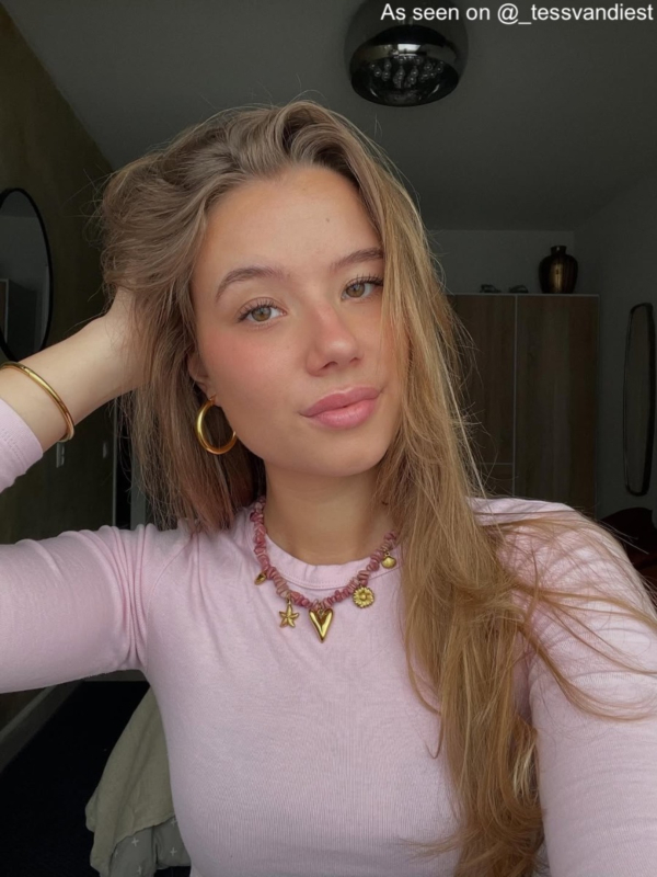 Influencer met gouden bedelketting met roze steentjes