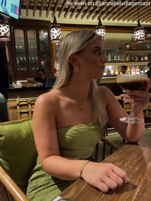 Gouden zeester oorbellen met groene top bij meisje met blond haar