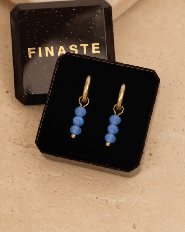 Gouden oorringetjes met blauwe steentjes in sieradendoosje