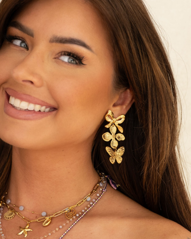 Model draagt triple charm oorbellen