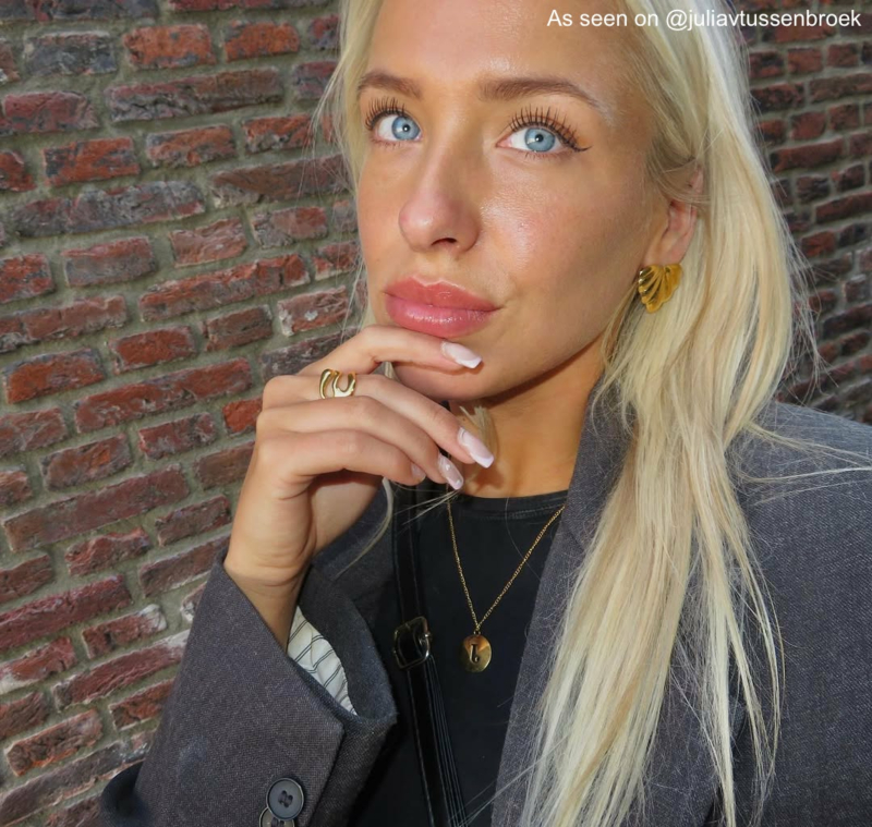 Influencer met gouden oorbellen, ring en initial ketting