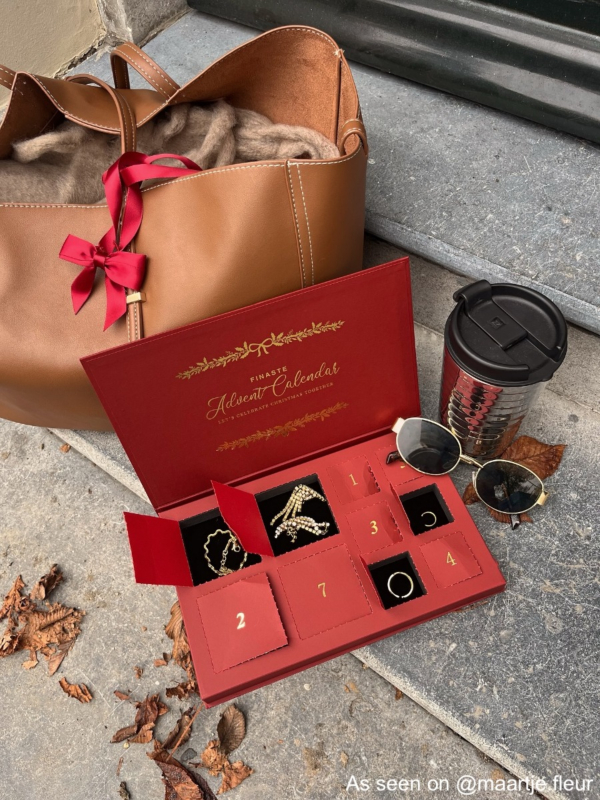 Adventkalender open naast tas, drinkbeker en zonnebril van influencer