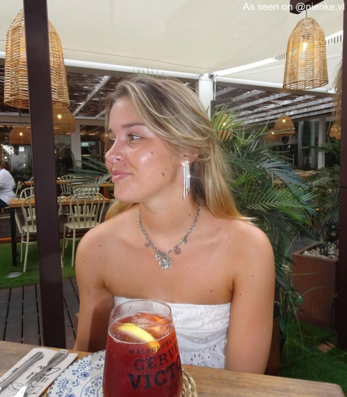 Influencer draagt zilveren ketting met bedels van bloemetjes