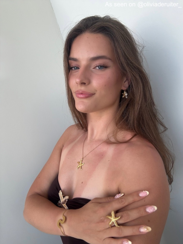 Influencer draagt gouden oorbel met zeester en parel