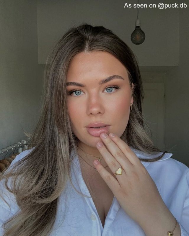 Influencer met gouden oorbellen, kettingen en ring met wit hartje