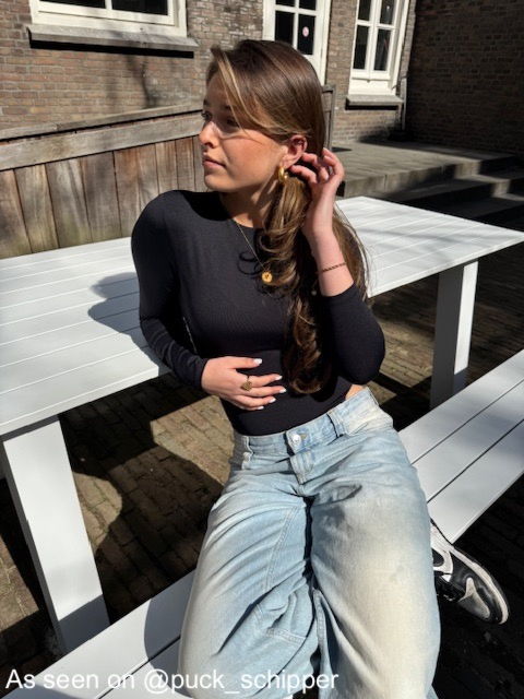 Influencer met gouden oorbellen en initial ketting