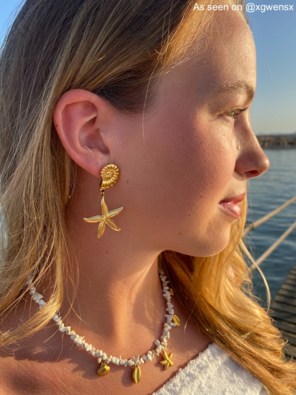 Influencer draagt gouden oorbellen met zeester en schelpje