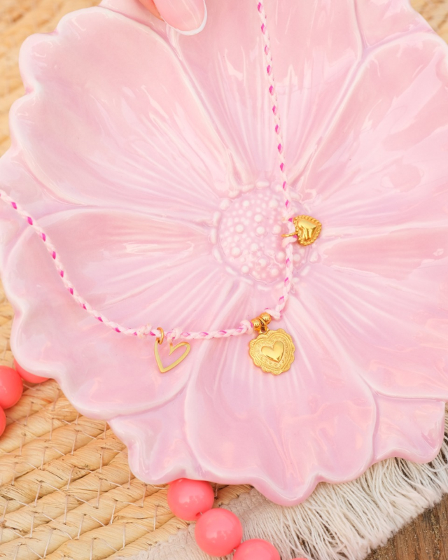 roze touw ketting met gouden bedeltjes op roze bloemen schaaltje