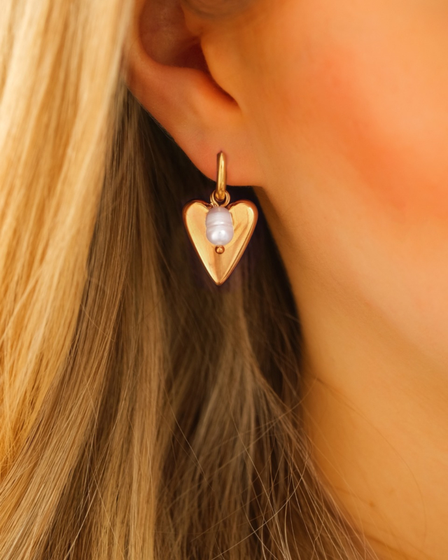 gouden hartjes oorbellen met pareltje bij vrouw met blond haar