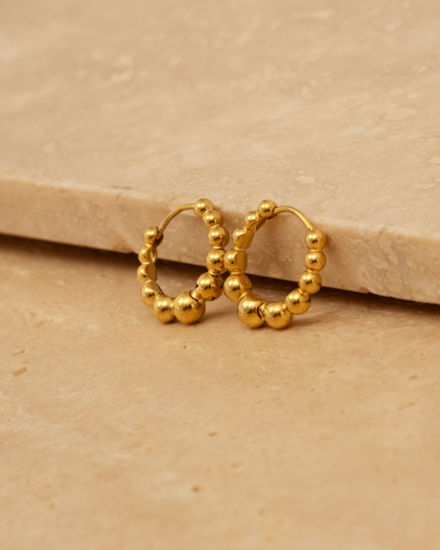 gouden bolletjes oorbellen op stenen ondergrond