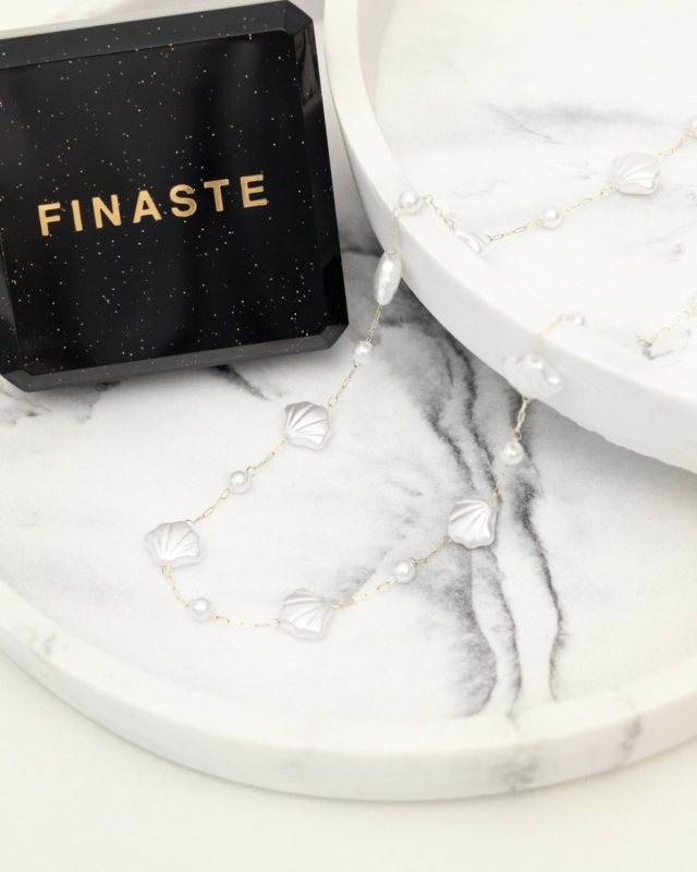 zilveren schelpen ketting met pareltjes bij een sieradendoosje