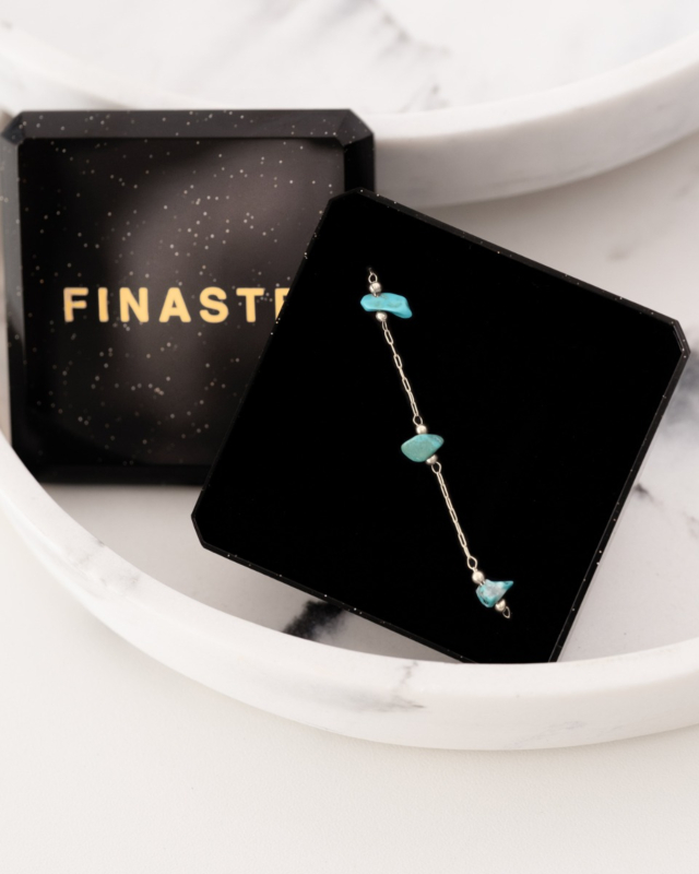 zilveren enkelbandje met turquoise steentjes in sieradendoosje met witte achtergrond