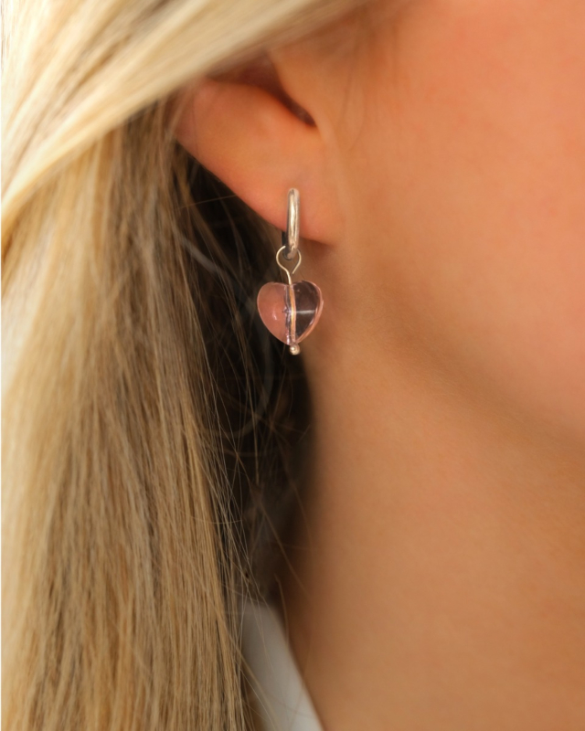 Model draagt zilver oorringetje met roze hartje