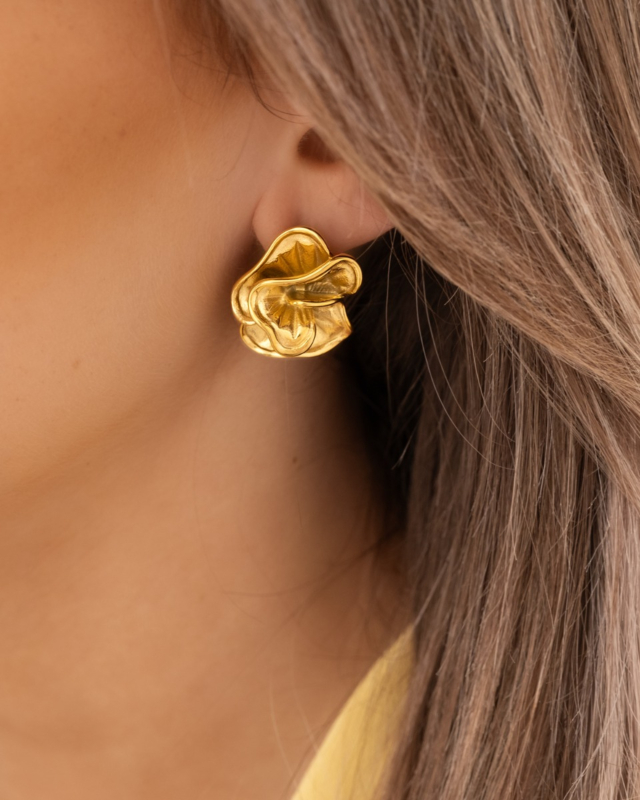 Model draagt gouden bloemen studs